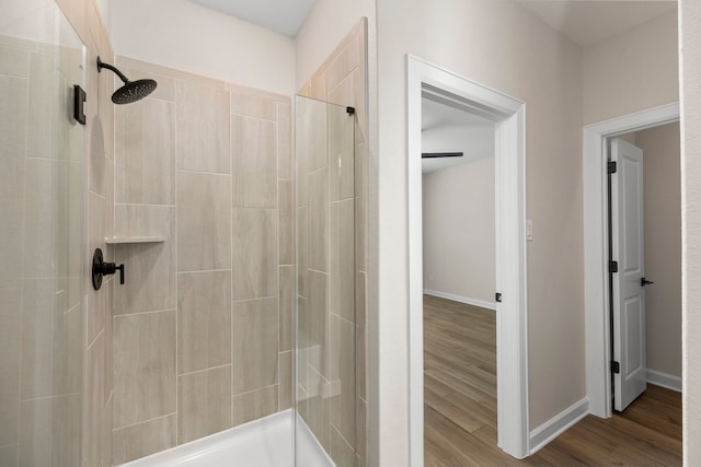 full bath featuring a stall shower, wood finished floors, and baseboards