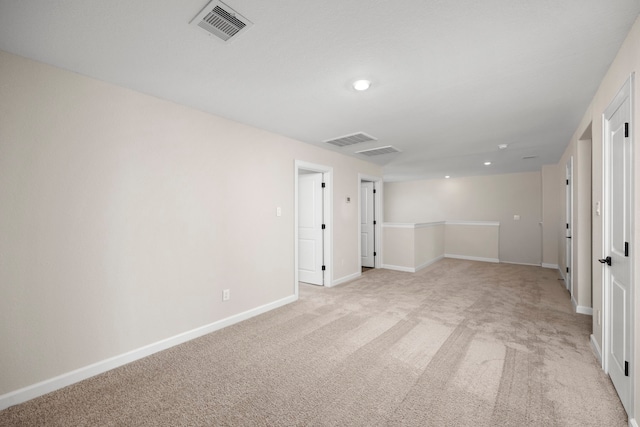 spare room with baseboards, visible vents, and light colored carpet