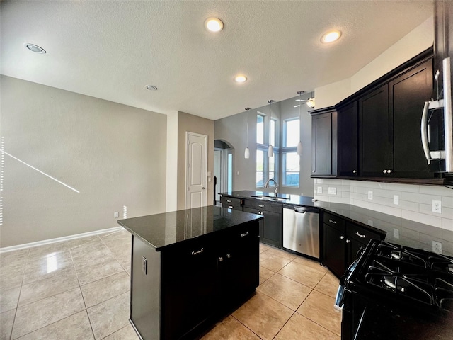 kitchen with tasteful backsplash, arched walkways, a kitchen island, stainless steel appliances, and a sink