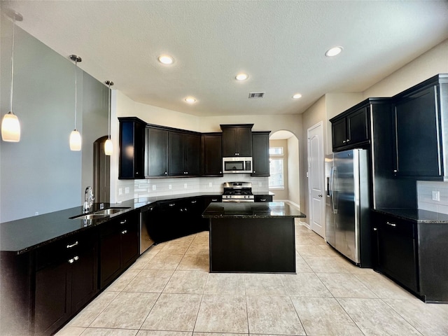 kitchen featuring arched walkways, a peninsula, a sink, visible vents, and appliances with stainless steel finishes