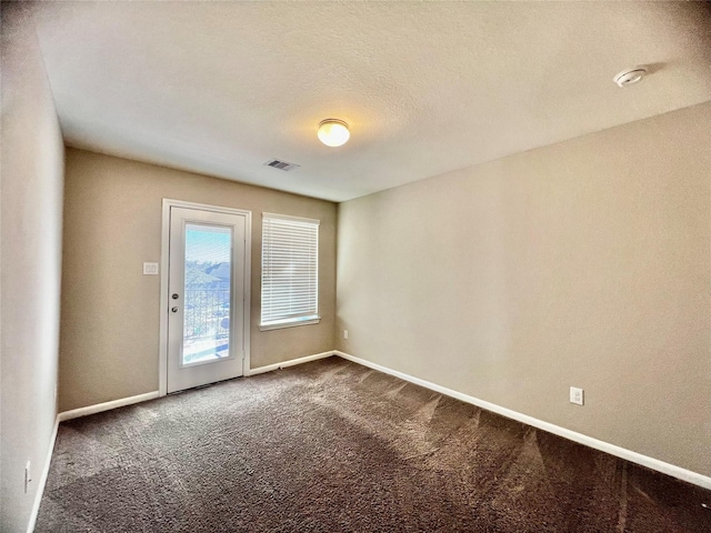 unfurnished room featuring baseboards, visible vents, dark colored carpet, and a textured ceiling