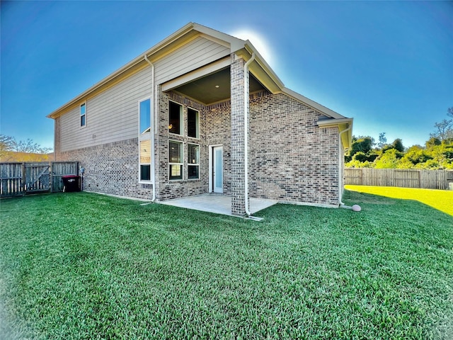 rear view of house featuring a patio area, a fenced backyard, a lawn, and brick siding