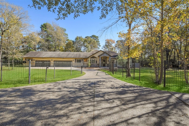 view of home's community with a fenced front yard, a yard, driveway, and an attached garage