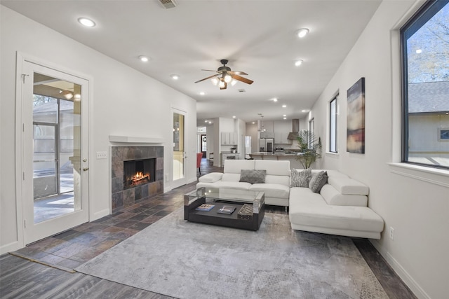 living area with baseboards, ceiling fan, stone finish floor, a fireplace, and recessed lighting