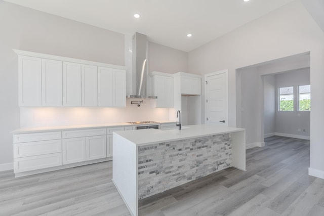 kitchen featuring white cabinets, wall chimney range hood, and light countertops