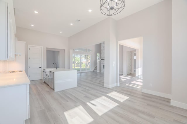 kitchen with white cabinetry, open floor plan, light countertops, light wood-type flooring, and decorative light fixtures