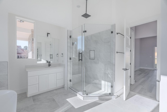 full bath featuring a high ceiling, baseboards, a shower stall, and vanity