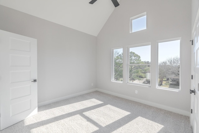 spare room featuring light carpet, high vaulted ceiling, ceiling fan, and baseboards