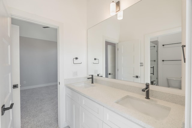 full bathroom featuring baseboards, a sink, toilet, and double vanity