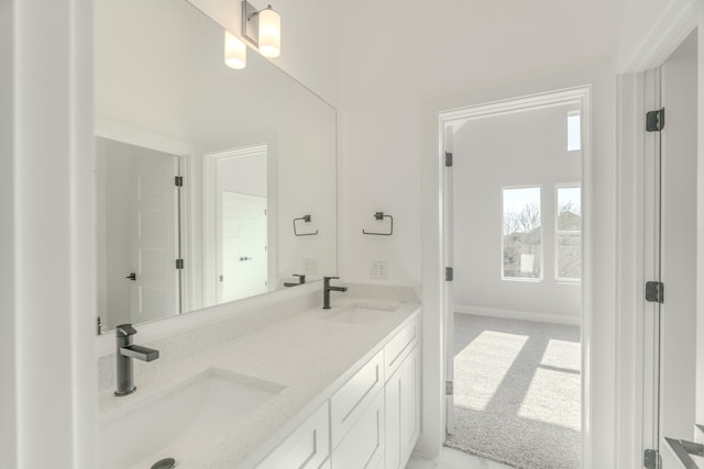 full bath featuring double vanity, a sink, and baseboards