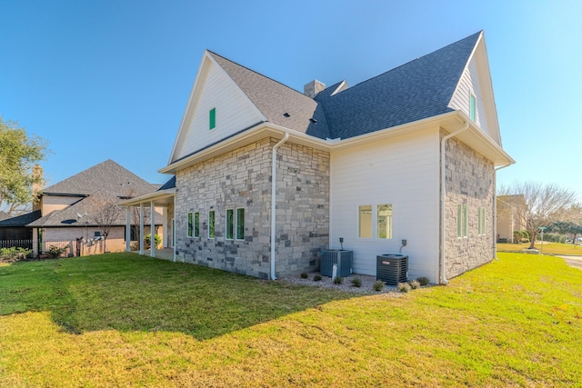 back of property with stone siding, a yard, a chimney, and central air condition unit