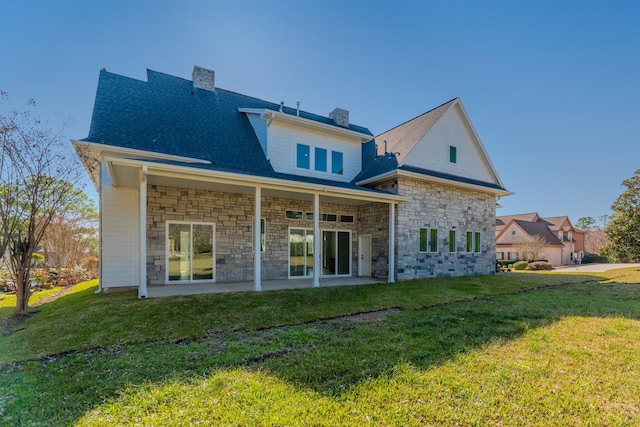 rear view of property with a patio, a shingled roof, a lawn, and a chimney