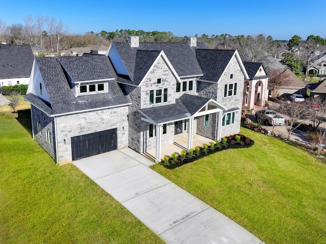 french country style house with a residential view, stone siding, an attached garage, and a front yard