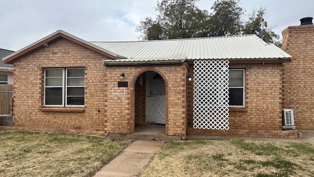 view of front facade with metal roof, a front lawn, a chimney, and brick siding