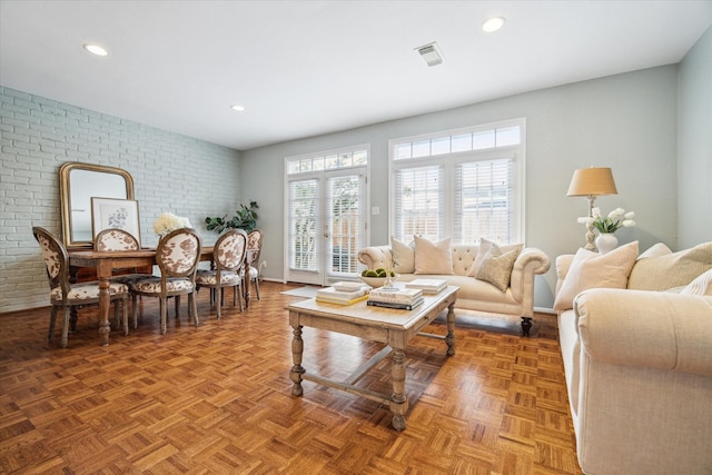 living room with brick wall, visible vents, and recessed lighting