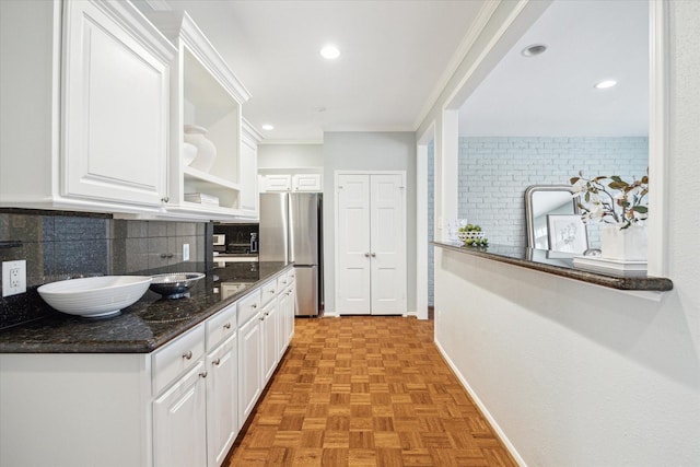 kitchen featuring backsplash, white cabinets, dark stone countertops, and freestanding refrigerator