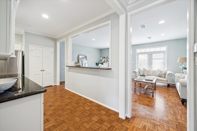 kitchen with visible vents, ornamental molding, open floor plan, white cabinetry, and baseboards