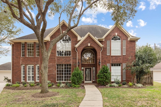 traditional-style house featuring brick siding, roof with shingles, and a front yard