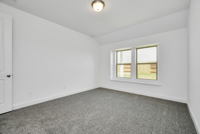 empty room with lofted ceiling, baseboards, and dark colored carpet