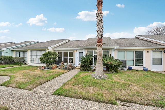 view of front of property with a shingled roof, a front yard, and stucco siding