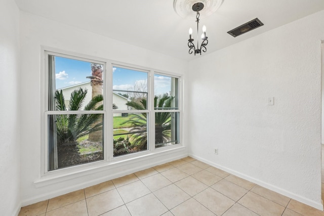 unfurnished room with baseboards, light tile patterned floors, visible vents, and an inviting chandelier