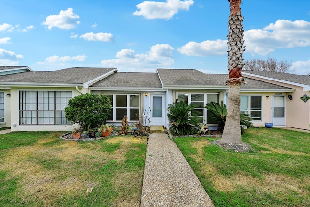 view of front of house featuring a shingled roof, a front lawn, and stucco siding