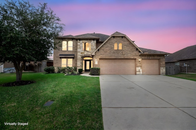 french country inspired facade featuring a front yard, concrete driveway, a garage, and stone siding