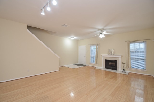 unfurnished living room featuring visible vents, baseboards, stairs, light wood-type flooring, and a ceiling fan