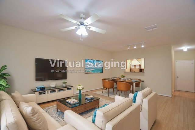 living area featuring baseboards, light wood-type flooring, visible vents, and a ceiling fan