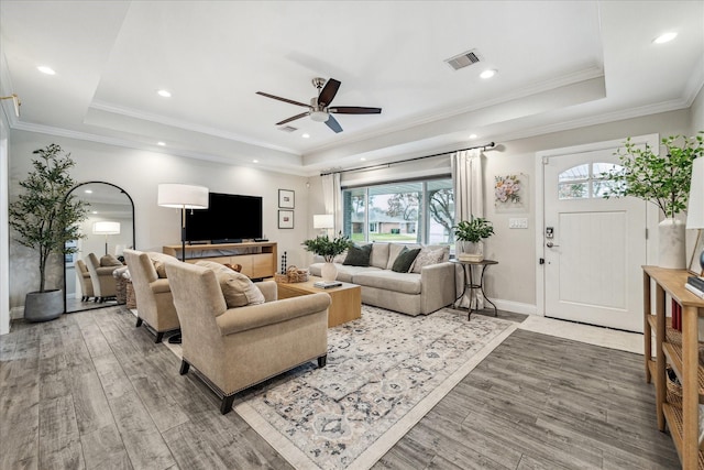 living area featuring visible vents, a raised ceiling, wood finished floors, and recessed lighting