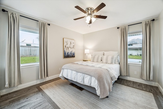 bedroom with multiple windows, ceiling fan, baseboards, and wood finished floors