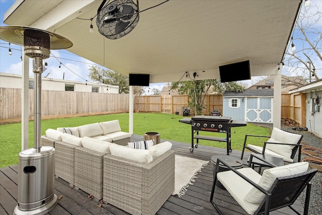 wooden deck featuring an outbuilding, area for grilling, a shed, a fenced backyard, and an outdoor living space