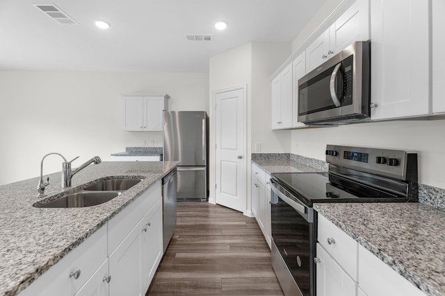 kitchen with white cabinetry, appliances with stainless steel finishes, light stone counters, and a sink