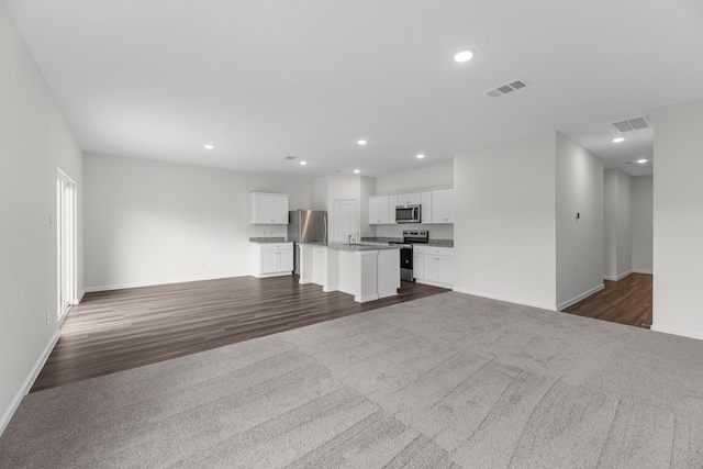 unfurnished living room featuring baseboards, visible vents, dark colored carpet, and recessed lighting