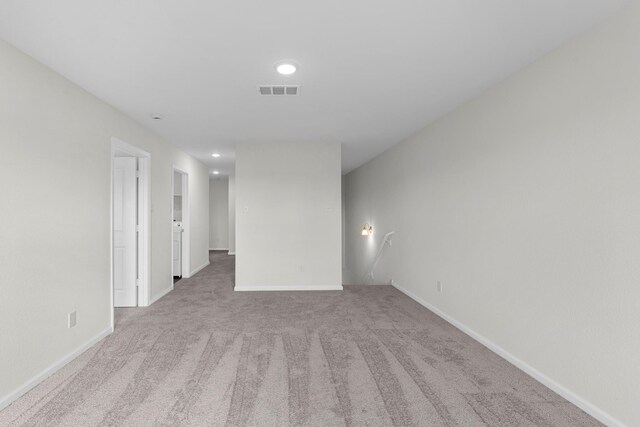spare room featuring baseboards, visible vents, and light colored carpet