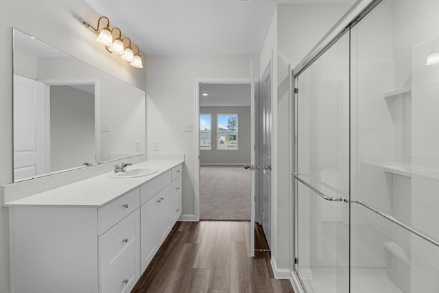 full bath with wood finished floors, a shower stall, vanity, and baseboards