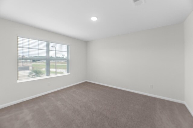 spare room with carpet, visible vents, and baseboards