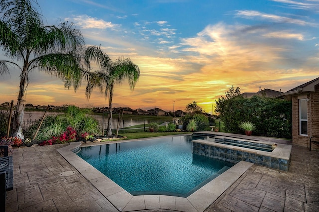 pool at dusk with a pool with connected hot tub, a fenced backyard, and a patio