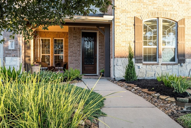 doorway to property featuring covered porch and brick siding