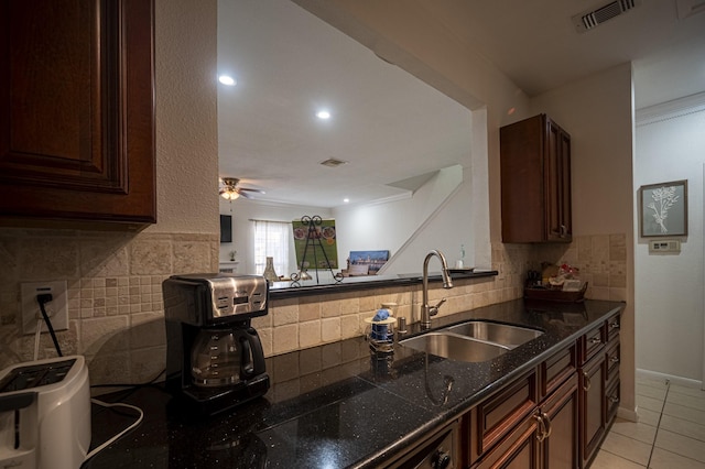 kitchen featuring light tile patterned floors, a sink, visible vents, decorative backsplash, and dark countertops