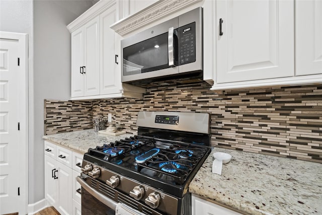 kitchen featuring tasteful backsplash, appliances with stainless steel finishes, light stone counters, and white cabinets