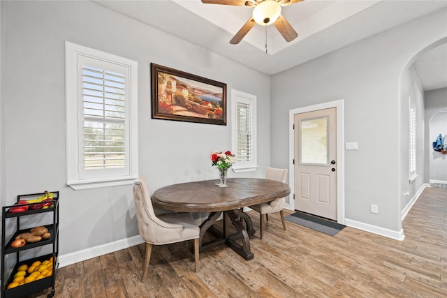 dining room featuring arched walkways, baseboards, and wood finished floors