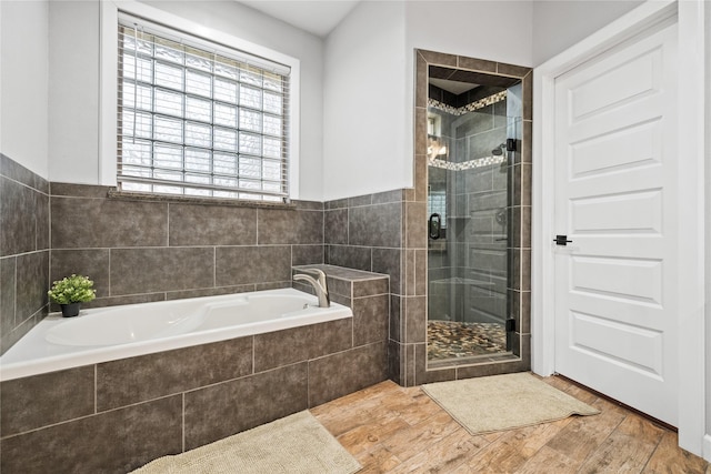 full bath featuring wood finished floors, a shower stall, and a bath