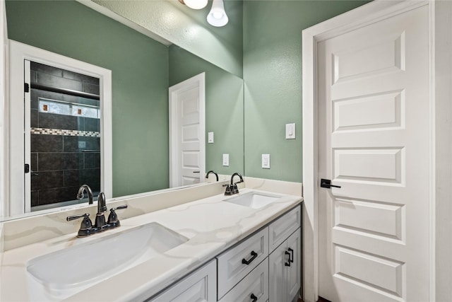 bathroom with double vanity, a shower, and a sink