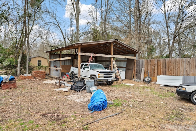 exterior space featuring a detached carport, fence, and an outbuilding