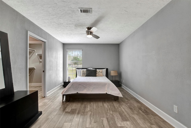 12203 W Morgan Dr, Houston, TX 77065 - bedroom featuring a walk in closet, wood finished floors, visible vents, and baseboards