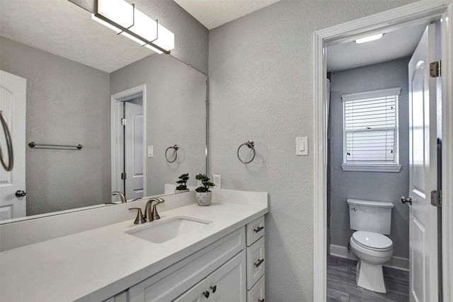 12203 W Morgan Dr, Houston, TX 77065 - bathroom featuring vanity, wood finished floors, baseboards, toilet, and a textured wall