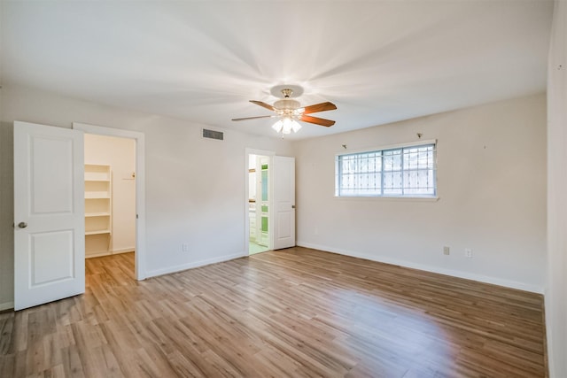 spare room featuring light wood-style floors, baseboards, visible vents, and ceiling fan