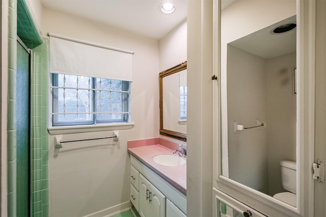 full bathroom featuring toilet, a shower with door, vanity, and baseboards