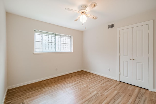 unfurnished bedroom featuring ceiling fan, visible vents, baseboards, light wood-style floors, and a closet